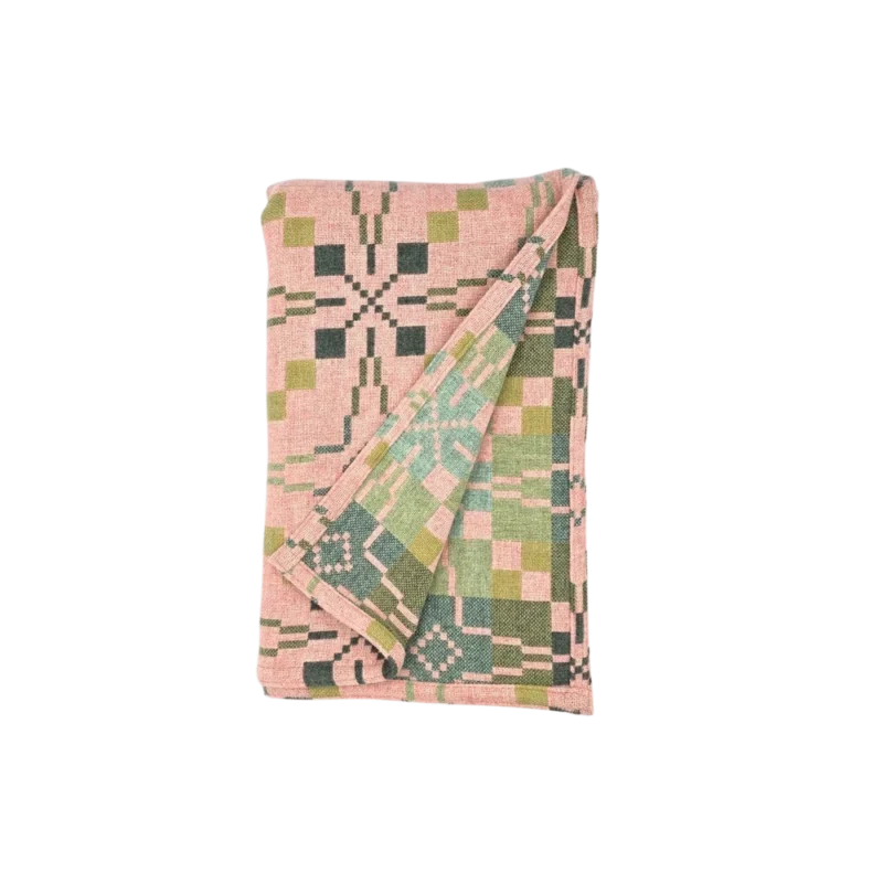 Melin Tregwynt Vintage Star Throw — reversible Welsh wool blanket, pink and green geometric double cloth pattern with folded corner showing complementary reverse side